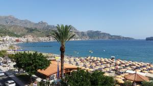 a beach with many umbrellas and a palm tree at Apartments Mikros in Giardini Naxos
