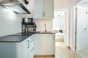 a kitchen with white cabinets and a sink and a bed at Casa centro Almedina in Almería +21 photos
