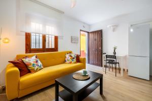 a living room with a yellow couch and a table at Casa centro Almedina in Almería