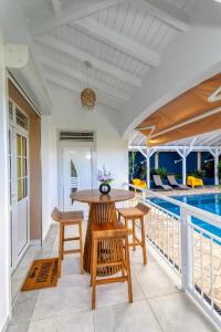 un patio avec une table et des chaises et une piscine dans l'établissement villa bouginvillier, à Pointe-Noire