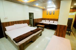 a bedroom with two beds in a room with yellow walls at Shree Sampatbai yatri ghar in Ujjain