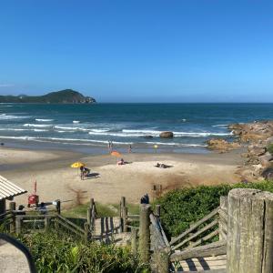 a beach with people on the sand and the ocean at Rosa blue in Imbituba