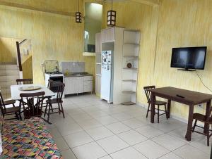 a kitchen with a table and chairs and a television at Rosa blue in Imbituba