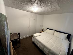 a bedroom with a white bed and a table at 3 bed unit Retreat near Ann Arbor King Bed in Ypsilanti