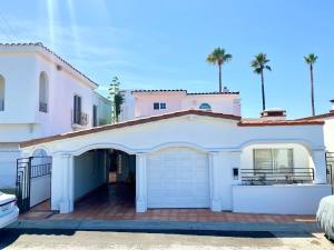 a white house with a garage and palm trees at Real Del Mar Tijuana Apt for 2 guests in Tijuana