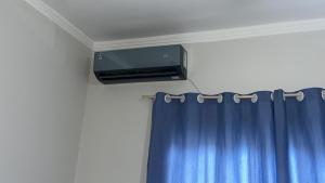 a tv on a wall next to a blue curtain at Casa do amor, vc pode ir andando até a praia in Itapoa