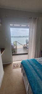 a bedroom with a view of the ocean from a balcony at Suites Villa Forte Santana in Florianópolis