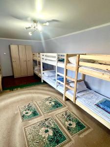 a room with multiple bunk beds with rugs on the floor at Хостел на Каримова in Almaty