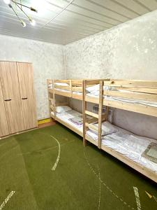 a room with two bunk beds and a green carpet at Хостел на Каримова in Almaty