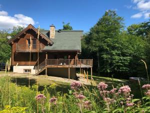 a log cabin with a porch and a deck at Chalet HURON 15 Guest EV Car in Labelle