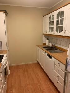 cocina con armarios blancos y suelo de madera en 2 bedrooms apartment, en Trondheim