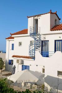 a white building with an umbrella in front of it at Haris Apartments in Armenistis