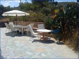 eine Terrasse mit einem Tisch, Stühlen und einem Sonnenschirm in der Unterkunft Haris Apartments in Armenistis