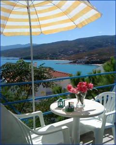 a table and chairs with an umbrella on a balcony at Haris Apartments in Armenistis