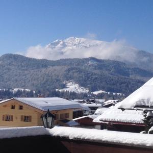 a mountain in the distance with snow on the roofs of buildings at Haus Christl Reit im Winkl, Kostenloser Parkplatz, Spülmaschine, 5 Minuten zum Ortszentrum, ruhige Lage, Wlan in Reit im Winkl