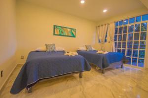 a bedroom with two beds and a large window at Hotel Villa Veral in San Sebastian Xolalpa