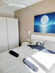 Schlafzimmer mit einem weißen Bett und einem TV an der Wand in der Unterkunft Bahia Sol Deluxe in Caleta de Fuste