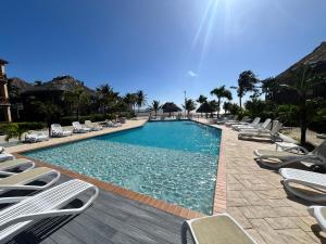 a large swimming pool with lounge chairs and the sun at Captain Morgan's Retreat in San Pedro