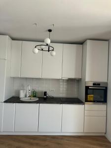 a kitchen with white cabinets and a sink at CityCenter Heart - Ultracentral & Panoramic View in Reşiţa