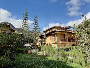 a yellow house with a garden in front of it at Hotel Mabey Urubamba in Urubamba