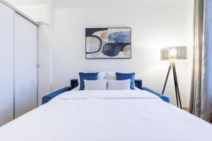 a bedroom with a large bed with blue pillows at Cosy Studio, close to Monaco Train Station in Beausoleil