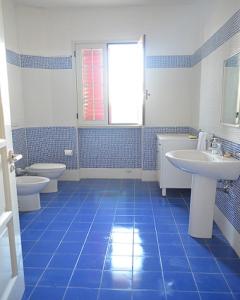 een blauw betegelde badkamer met 2 wastafels en 2 toiletten bij Villetta Summer in Porto Cesareo