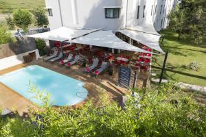 - une vue sur une piscine avec des chaises et un bâtiment dans l'établissement Hôtel de l'Arbois, à Aix-en-Provence