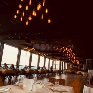 a restaurant with people sitting at tables in a room with windows at Pirshagi Villa in Baku