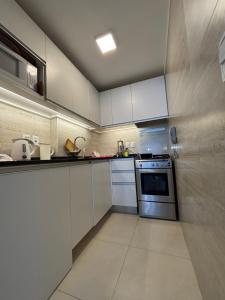 a kitchen with white cabinets and a stove at DEPARTAMENTO APOLO PUNTA DEL ESTE DEPTO 201 SEGUNDO PISO sobre CALLE PRINCIPAL GORLERO in Punta del Este