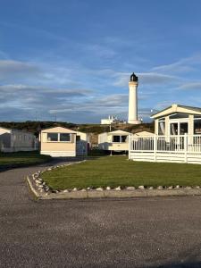 a lighthouse with a white house and a lighthouse at Little Cha-Am Caravan Hire at Silver Sands in Lossiemouth