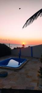 a sunset over a swimming pool with the ocean at Chalés Luz do Luar in Aracati