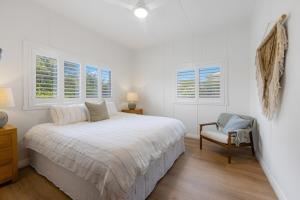 a white bedroom with a bed and a chair at Bonny Chill - Walk to beaches, pet friendly in Bonny Hills