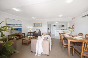 Una sala de estar con un sofá y un comedor. en 205 South Pacific Apartment - pool and aircon, en Port Macquarie