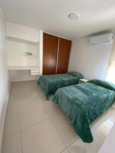 two beds with green comforters in a room at Dpto 9 DE JULIO in Villa María