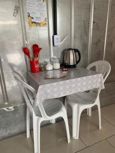 a table with two chairs and a tea kettle on it at Vila do Chaves Casa da Popis 23 in Itajaí