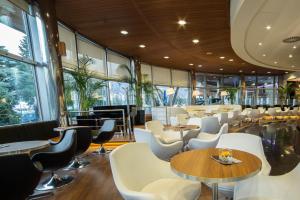 un restaurant avec des chaises blanches, des tables et des fenêtres dans l'établissement Perla, Resort & Entertainment, à Nova Gorica
