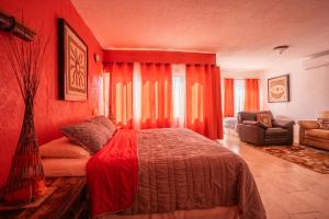 a bedroom with red walls and a bed and a couch at Tranquility House Cancun in Cancún