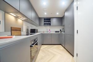 伯明翰Luxury Nostalgic City Centre Stay with Pool Table, Netflix, Sofa bed, Sleeps 6, Nostalgia Stays的厨房配有白色橱柜和木地板