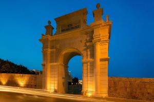a building with an arch at night at The Westin Dragonara Resort, Malta in St. Julianʼs