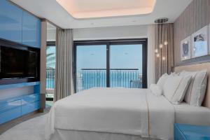 a bedroom with a large white bed and a television at The Westin Dragonara Resort, Malta in St. Julianʼs
