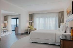 a bedroom with a large white bed and a living room at The Westin Dragonara Resort, Malta in St. Julianʼs