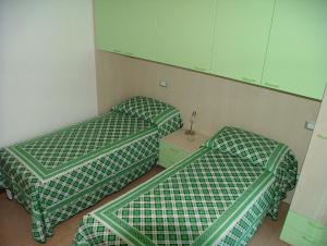 two beds in a room with green and white covers at Residence Magnolia in Grado