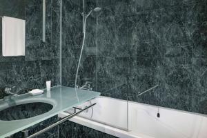 a bathroom with a shower and a sink and a tub at AC Hotel Genova by Marriott in Genoa