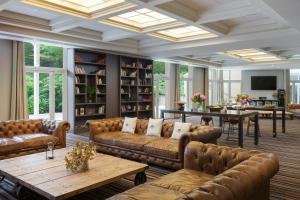 a living room with leather couches and a table at Renaissance Paris Hippodrome de St. Cloud Hotel in Rueil-Malmaison