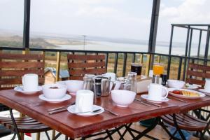 a wooden table with plates of food on a balcony at Camp Ayza Elementaita in Kariandus +35 photos