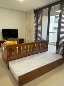 a large wooden bed in a room with a television at Loft Charmoso com Rooftop no Vila das Dunas in Flecheiras +2 photos