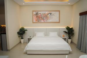 Un dormitorio con una cama blanca y un cuadro en la pared. en Gelis Gede Cottages, en Uluwatu 43 fotos más