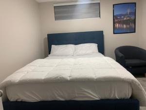 ein großes Bett mit blauem Kopfteil und ein Stuhl in der Unterkunft The Cozy Oasis in Winnipeg