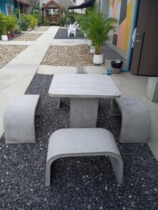a picnic table and two benches in front of a building at SK Hometel Samui Airport in Bang Rak Beach