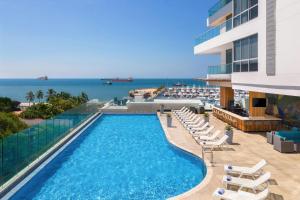 a swimming pool with chairs and the ocean in the background at AC Hotel By Marriott Santa Marta in Santa Marta